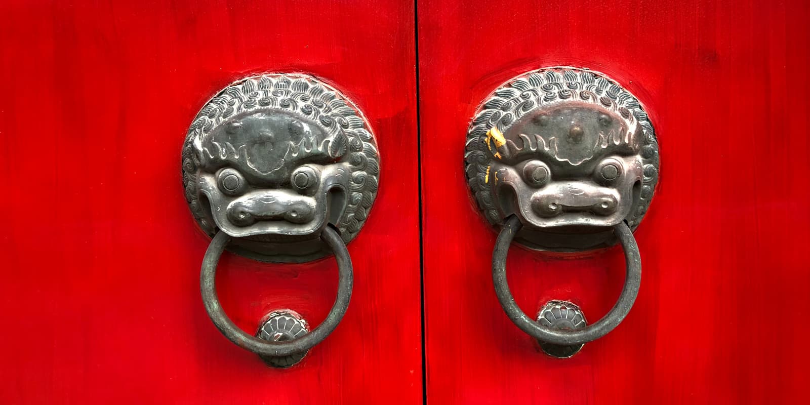 Nahaufnahme einer verschlossenen, roten Türe mit zwei chinesischen Türknöpfe